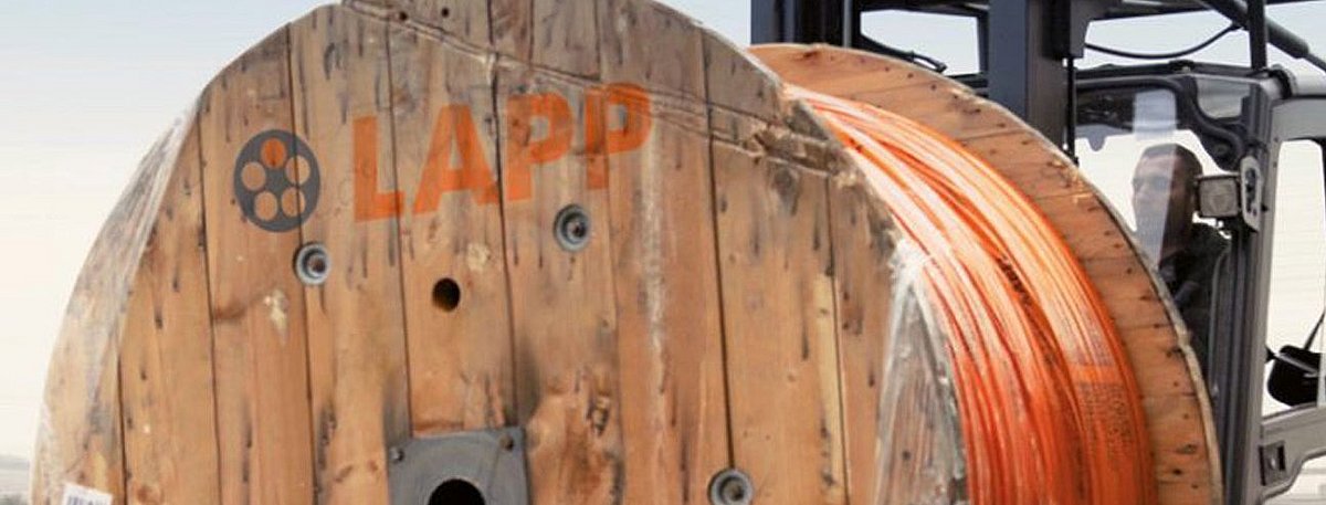 Eine große Kabeltrommel wird von einem Gabelstabler transportiert.