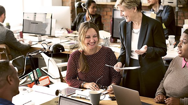 Dargestellt sind Angestellte in einem Großraumbüro.