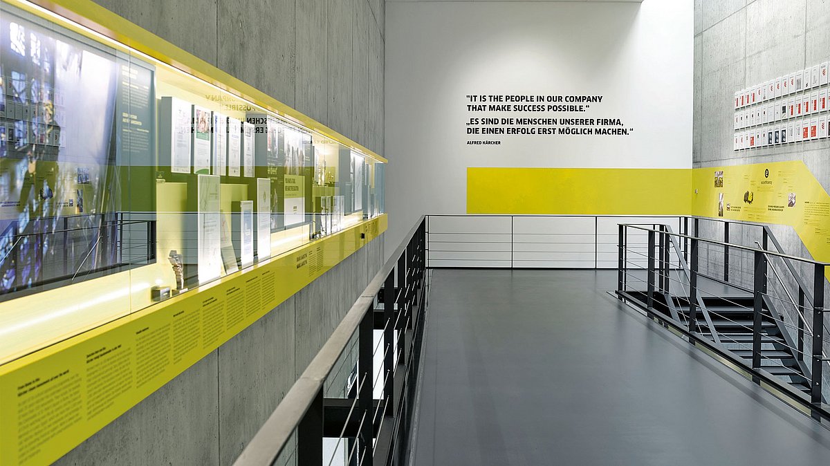 Eine Etage im Treppenhaus der Firma Kärcher enthält auf einer Wandfläche lange Glasvitrinen mit Informationselementen. An den anderen Wänden befinden sich weitere zahlreiche Informationen.