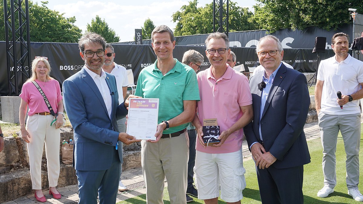 Staatssekretär Andre Baumann stehet neben drei Mitgliedern SV Böblingen und überreicht die N!-Charta Sport Urkunde.