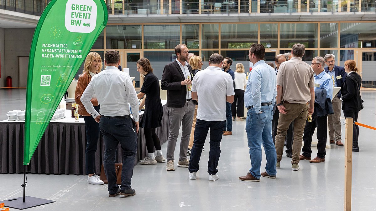Foyer des SpOrt Stuttgarts gefüllt mit Teilnehmenden und einer Green Event Beachflag an der Seite.
