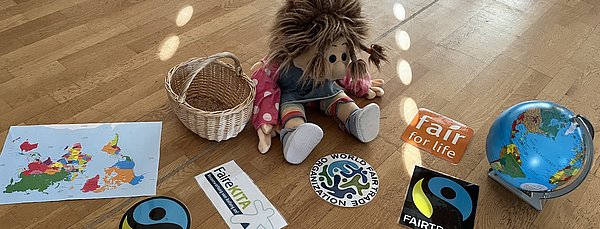 Ilse-Lotte, unsere Handpuppe führt das Thema im Stuhlkreis ein. Sie bringt einen Korb mit fairen Logos mit.