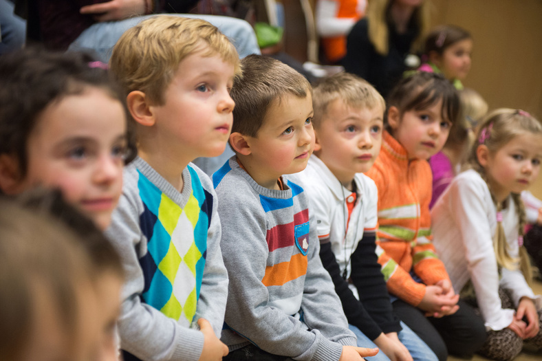 Drei Mädchen und drei Jungen im Kindergartenalter sind in der Hocke auf dem Boden schauen nach vorn und hören zu.
