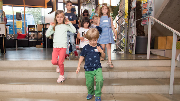 Vier Kindergartenkinder laufen eine Treppe herunter