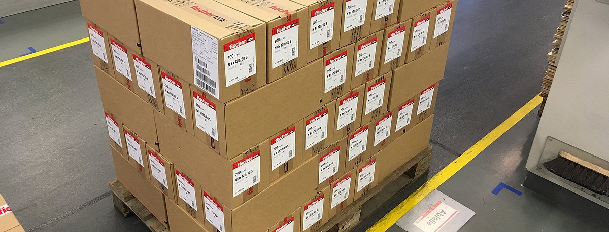 Eine Palette ist beladen mit vielen Karton, bei denen anstatt einer Strechfolie als Transportsicherung ein Klebeverfahren eingesetzt wird.