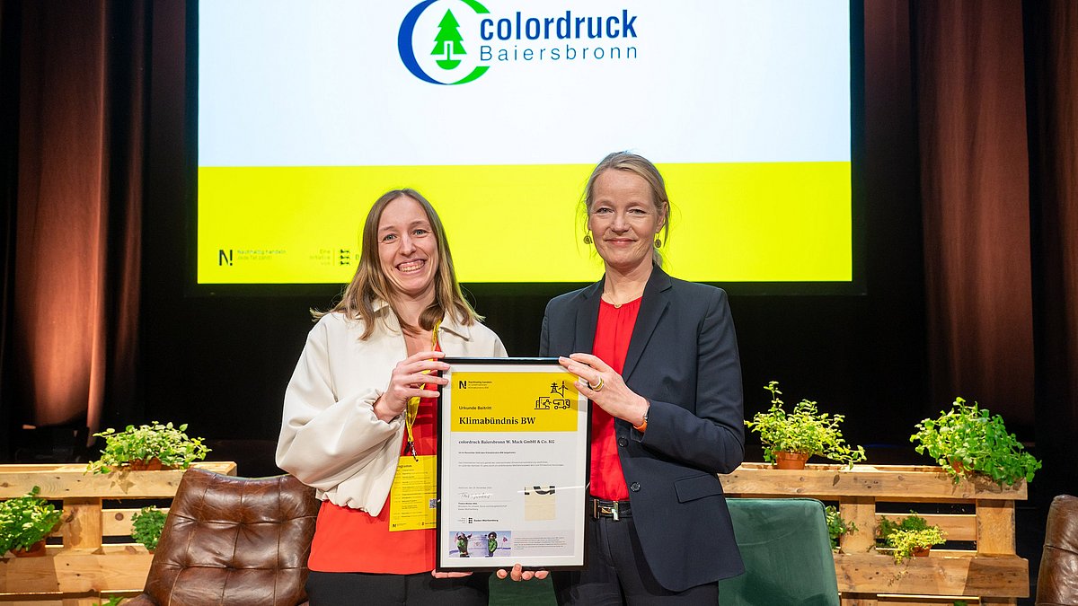 Urkunde zum Klimabündnis BW für eine Vertreterin von colordruck, überreicht von Umweltministerin Thekla Walker.