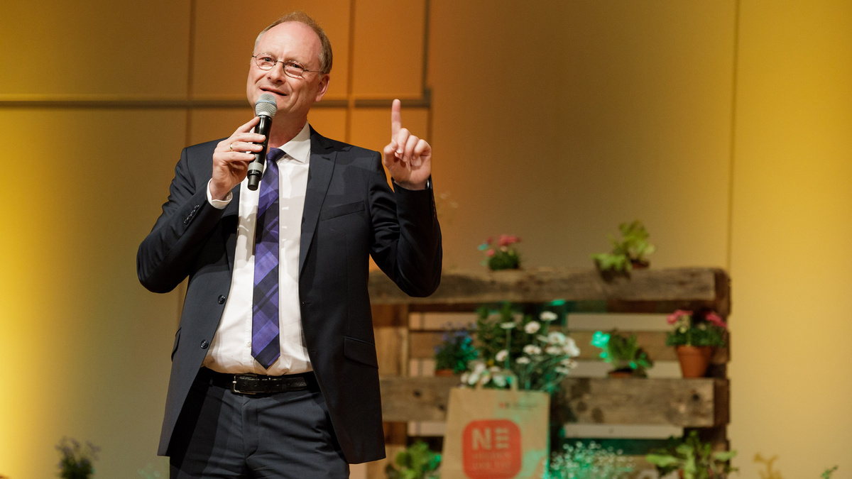 Der Moderator Sven Plöger steht auf einer Bühne und spricht in ein Mikrofon.