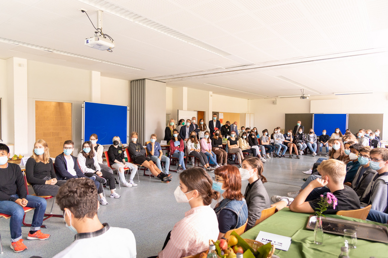 Ein Saal voller Schüler, die jemandem zuhören.