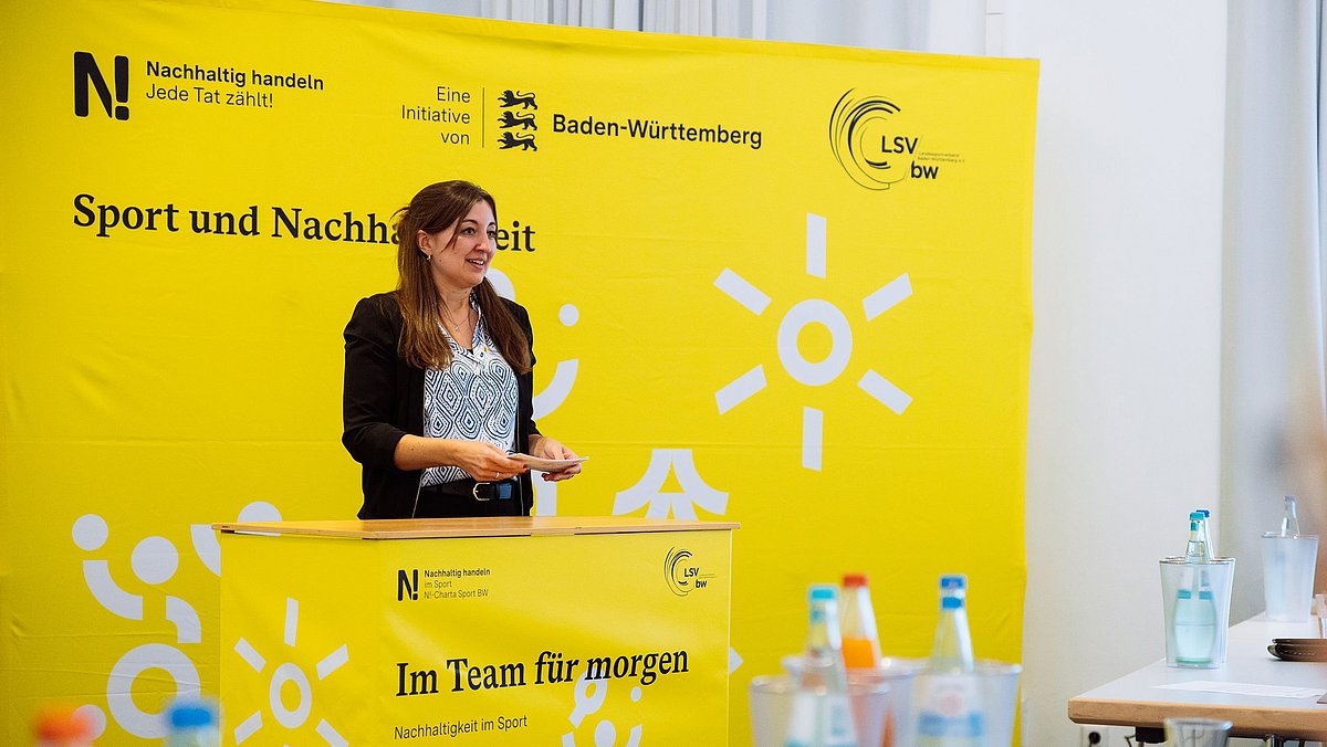 Frau spricht am Rednerpult vor den Teilnehmenden des Vernetzungstreffens