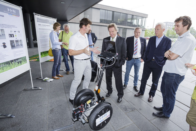 Minister Untersteller steht mit einer Gruppe von Personen vor einem Segway.