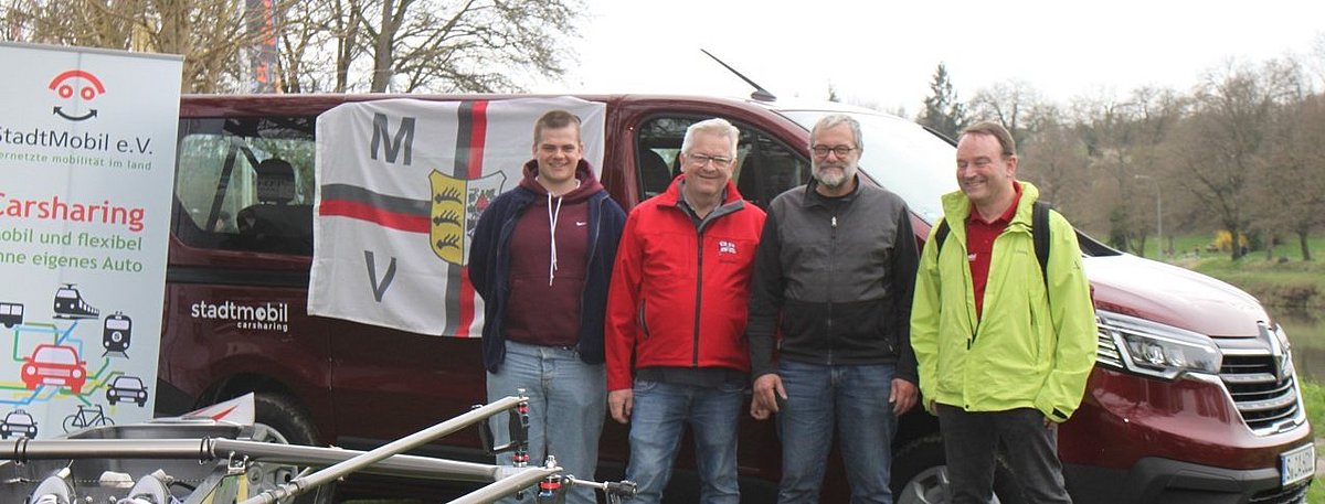 Vier Mitglieder des Marbacher Rudervereins stehen vor einem großen Van und lächeln