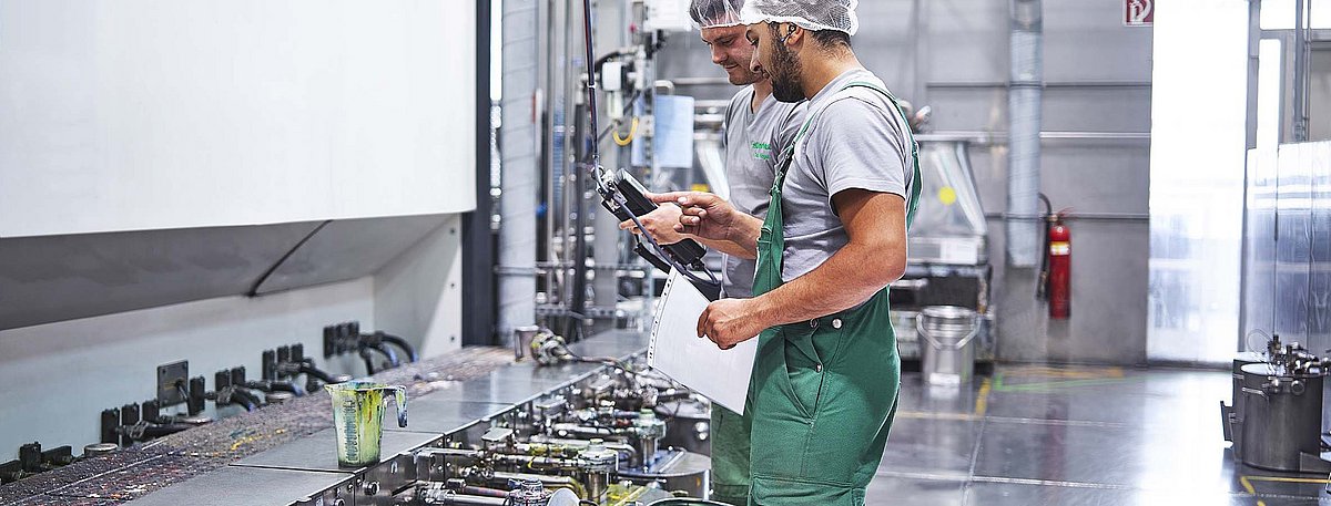 Zwei Mitarbeiter bereiten die Druckfarbenversorgung vor.