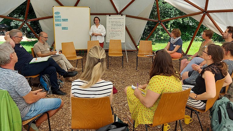 Workshoprunde unter einem Zeltdach.