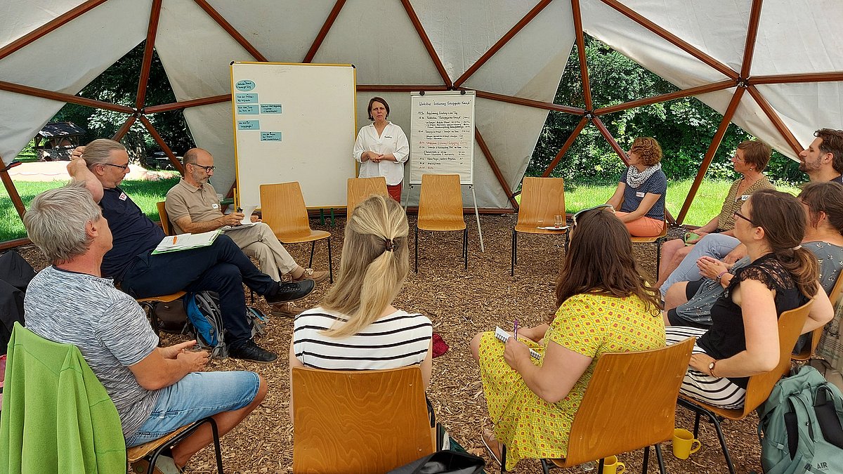 Workshoprunde unter einem Zeltdach.
