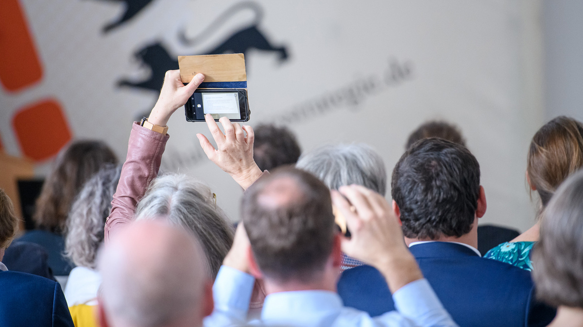 Aus einem Publikum heraus werden mit Smartphones  Fotos gemacht.