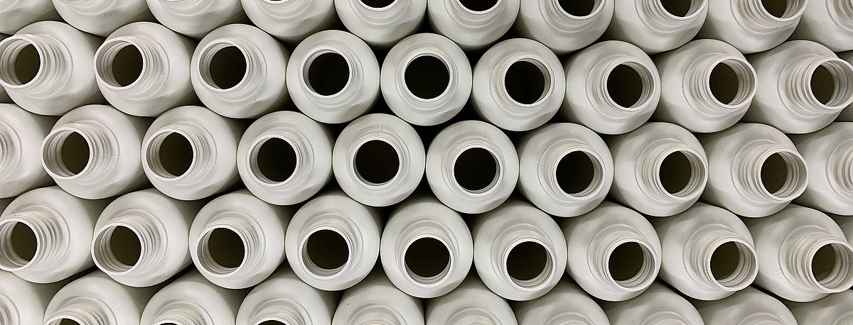 Ansicht vieler gleicher Recyclingflaschen von oben. Die Flaschen sind leer und ohne Verschlüsse. 