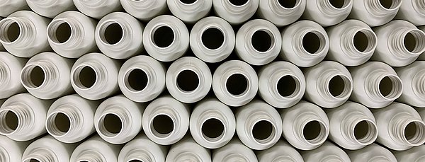 Ansicht vieler gleicher Recyclingflaschen von oben. Die Flaschen sind leer und ohne Verschlüsse. 