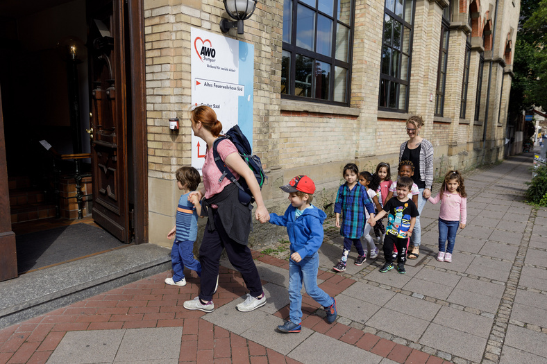 Erzieherinnen laufen mit Kindern ins alte Feuerwehrhaus in Stuttgart
