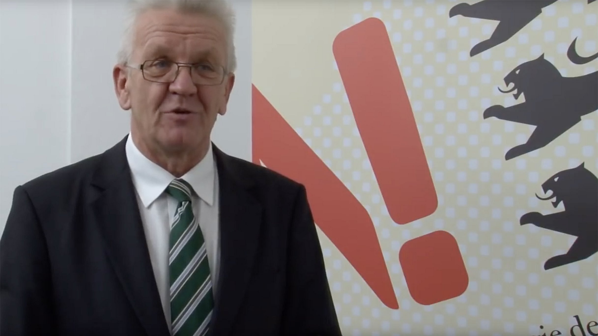Ministerpräsident Kretschmann steht vor einer Rückwand mit dem Logo der Nachhaltigkeitsstrategie Baden-Württemberg.