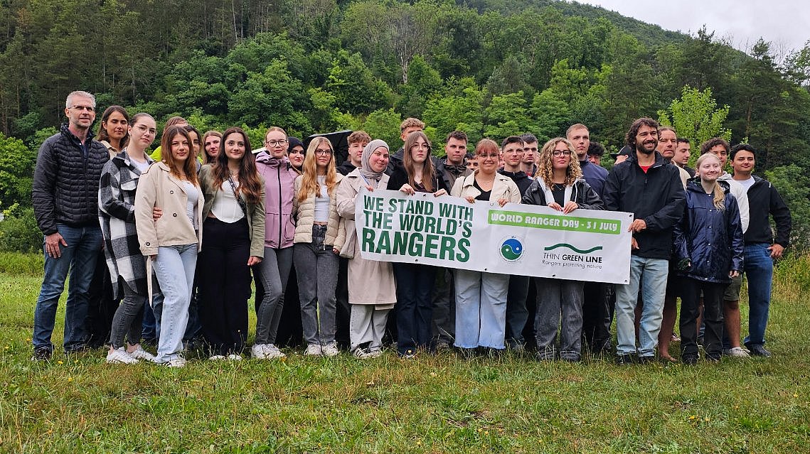Beteiligte Menschen am Projekt des World Ranger Days 2025 stehen zusammen und halten ein Banner.