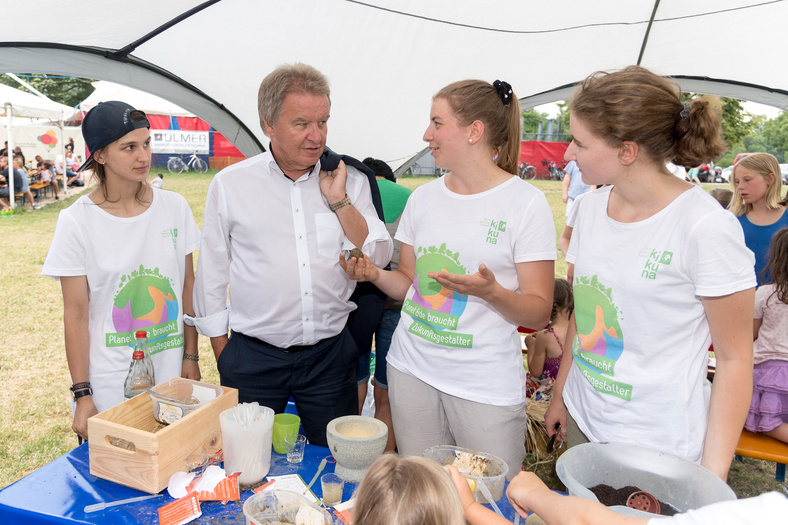 Herr Minister Franz Untersteller unterhält sich mit drei Frauen an einem Stand auf dem Ulmer Zelt