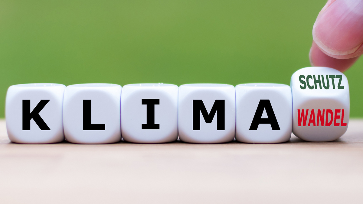 Klimawandel - Klimaschutz Fünf Spielwürfel mit Buchstaben bilden das Wort Klima. Auf einem letzen Würfel in der Reihe steht auf einer Würfelfläche das Wort Wandel und auf der anschließenden das Wort Schutz. Dieser Würfel wird von zwei Fingern auf Kippstellung zwischen Wandel und Schutz gehalten.