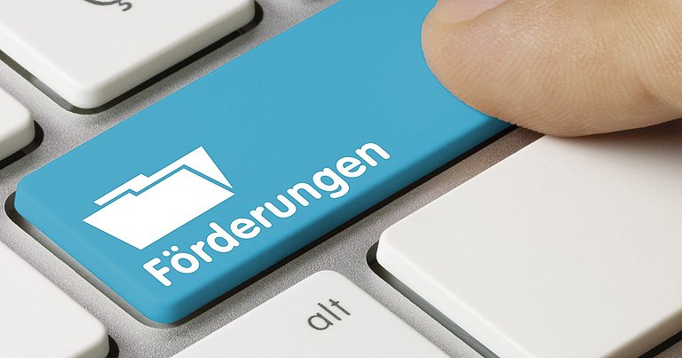 Tastatur mit einer Taste "Förderungen" und einem Finger, der auf diese Taste drückt.