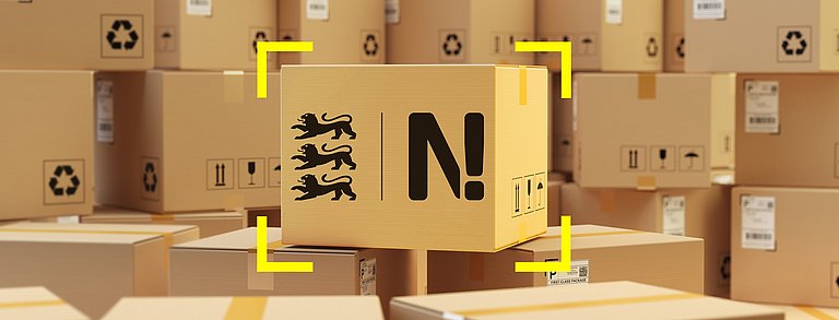 Viele Versandpakete sind übereinandergestapelt. In der Mitte steht ein Paket mit dem Logo der Nachhaltigkeitsstrategie Baden-Württemberg.
