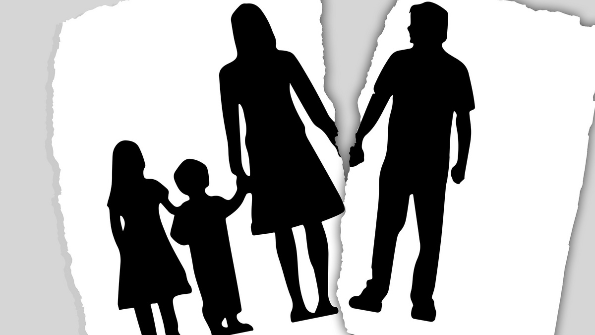 Ein ausgefranstes Papierblatt mit dem Scherenschnitt einer Familie ist zerrisen. Auf einem Teil sieht man den Vater der Familie auf dem anderen die Mutter mit einem Mädchen und einem Jungen.