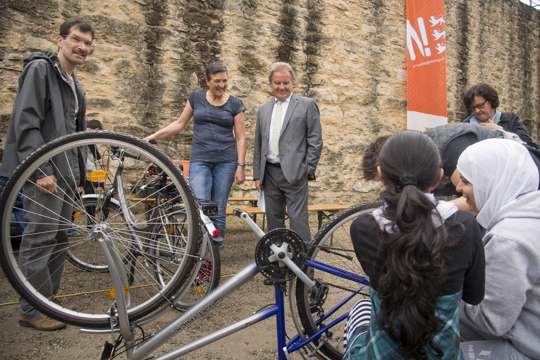 Minister Franz Untersteller beobachtet dir Reparatur einer Fahrrads 