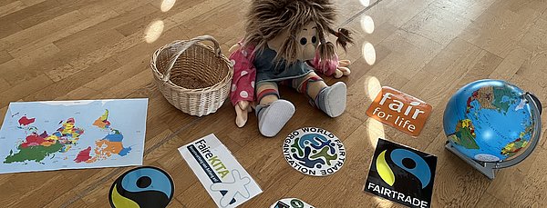 Ilse-Lotte, unsere Handpuppe führt das Thema im Stuhlkreis ein. Sie bringt einen Korb mit fairen Logos mit.