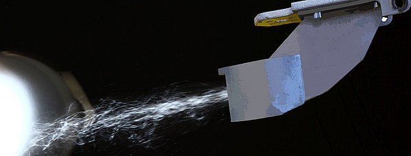 Materialfasern werden gegen ein Werkstück geblasen.