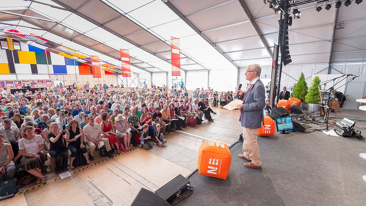 Der Moderator der Preisverleihung beim Deutschen Ev. Kirchentag in Stuttgart spricht zum vollbesetzten Auditorium.