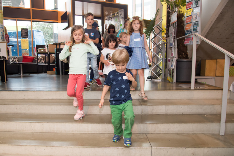 Vier Kindergartenkinder laufen eine Treppe herunter