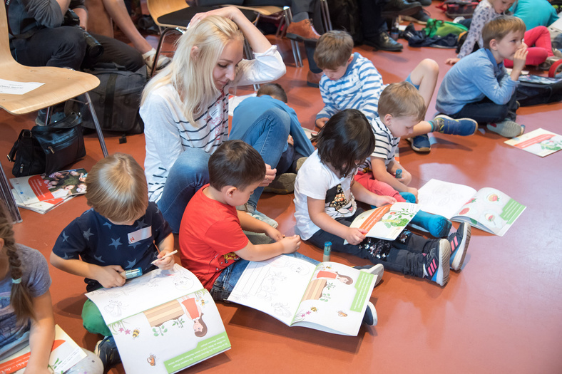 Kinder spielen mit Malbüchern auf dem Boden sitzend