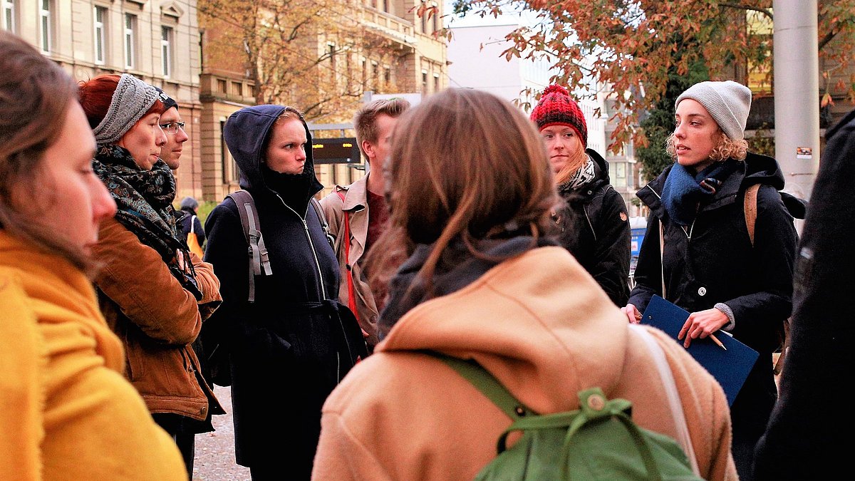 Aufnahme von einer Gruppe von Menschen, die draußen im Kreis stehen.
