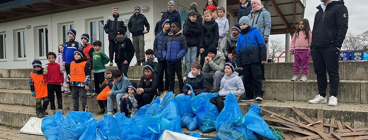 Mehrere Vereinsmitglieder von SV Blau-Weiß Wiehre stehen vor blauen Müllsäcken.