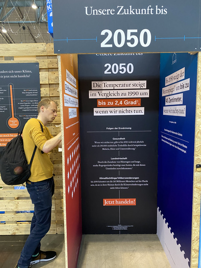 Ein Mann steht neben einer Kabine mit der Aufschrift "Unsere Zukunft bis 2050".