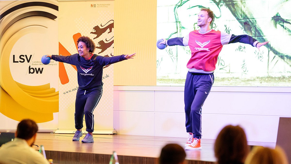 Auf der Bühne tanzen ein junge Frau und ein junger Mann mit Bällen.
