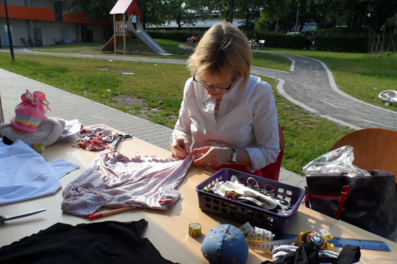 Frau näht an einem T-Shirt während einer Upcycling-Aktion