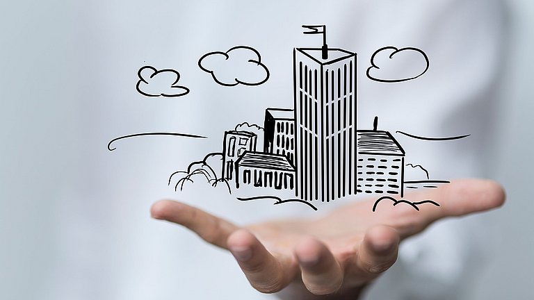 Über einer Handfläche schwebt unterschiedliche gezeichnete Häuser.