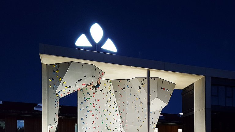 Große beleuchtete Kletterwand am Abend