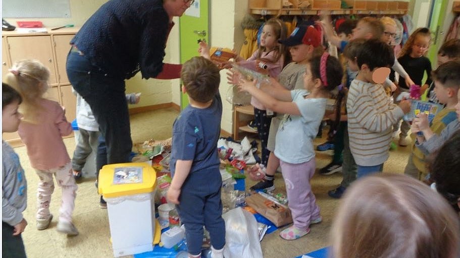 Alle Kinder helfen mit den Müll in die richtige Mülleimer zu sortieren.