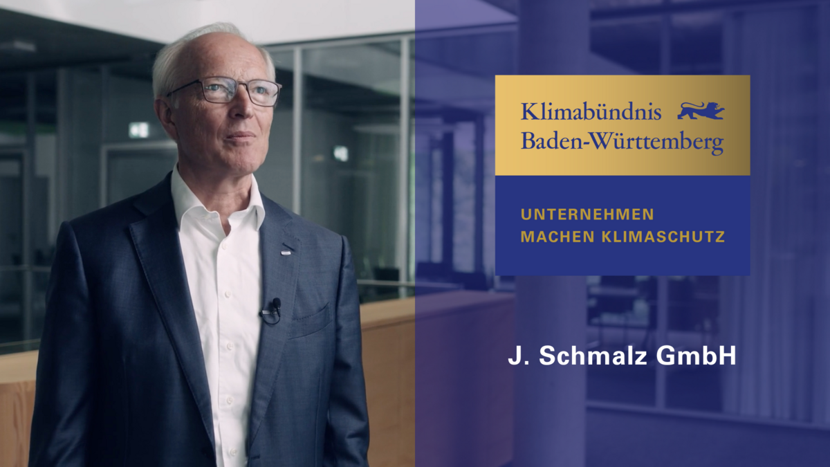 Rechts das Logo in gold und blau "Klimabündnis Baden-Württemberg, Unternehmen machen Klimaschutz" mit der Aufschrift J. Schmalz GmbH. Rechts ein unternehmensvertreter der Firma J. Schmalz..