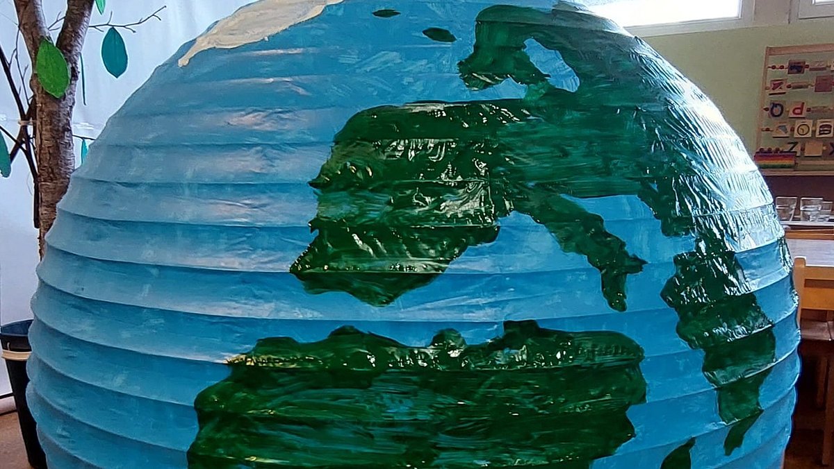 Unsere eine Welt - Es wurden Familienfotos aller Kita-Familien aufgehangen und diese Erde ziert unseren Eingangsbereich