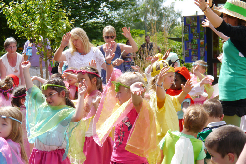 als bunte Feen verkleidete Kinder des katholischen Kindergarten St. Marien tanzen in der Sonne