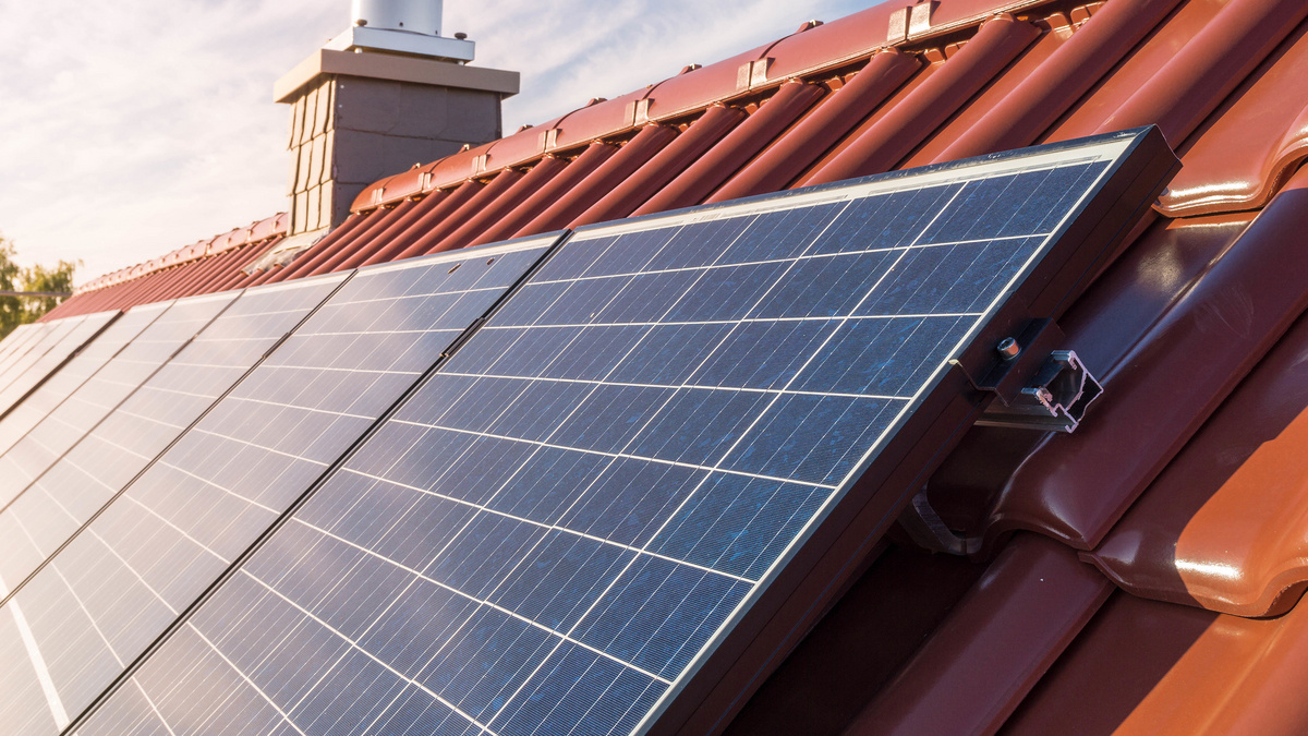 Mehrere Fotovoltaikmodule auf einem großen Dach liefern Strom von der Sonne.