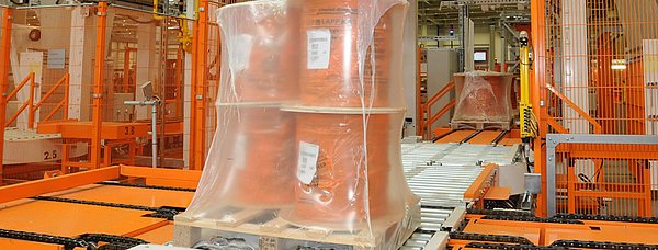 Eine Palette mit vier Kabeltrommeln sind von einer Sehrumpffolie umgeben. Sie verlassen gerade die Sehrumpfanlage.