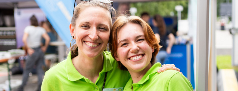 Jobfestival 2024 Team Zwei sympathische junge Frauen die sich den Arm über die Schulter legen und lachen