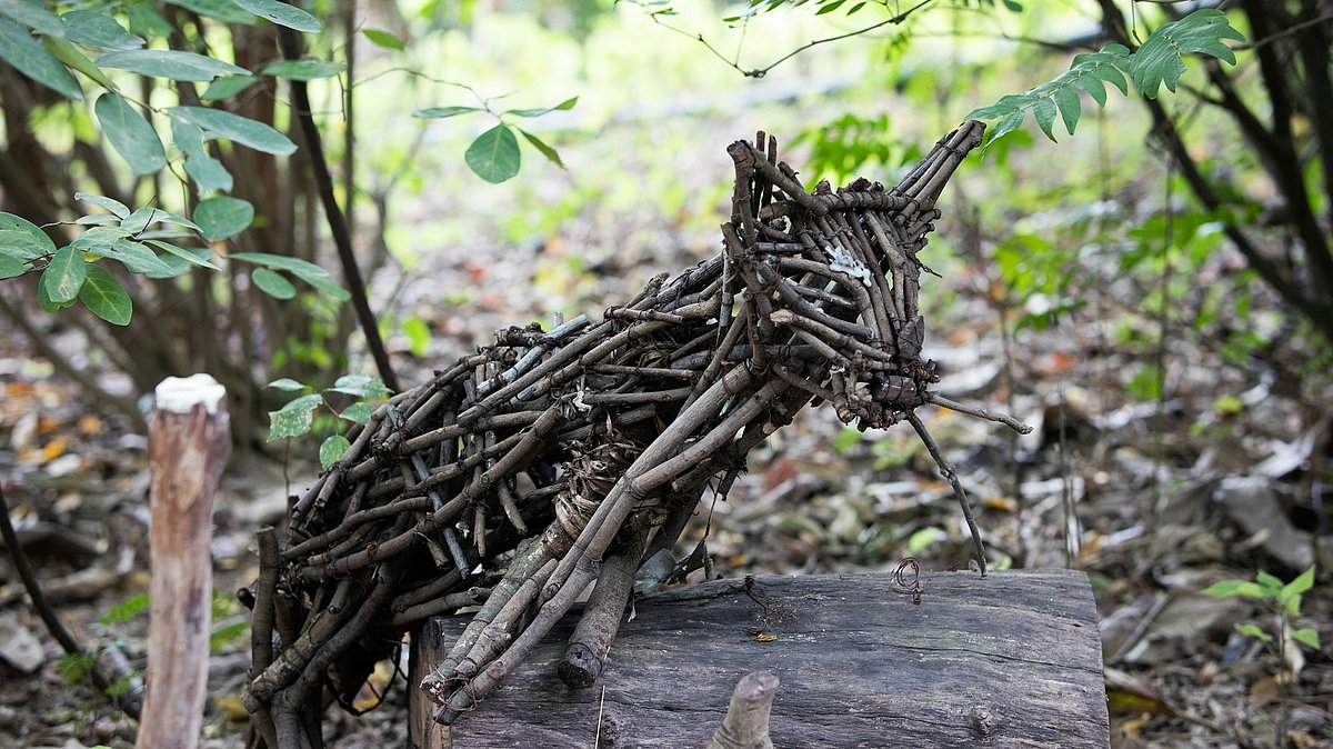 Ein aus Hölzchen gebauter Fuchs steht im Wald